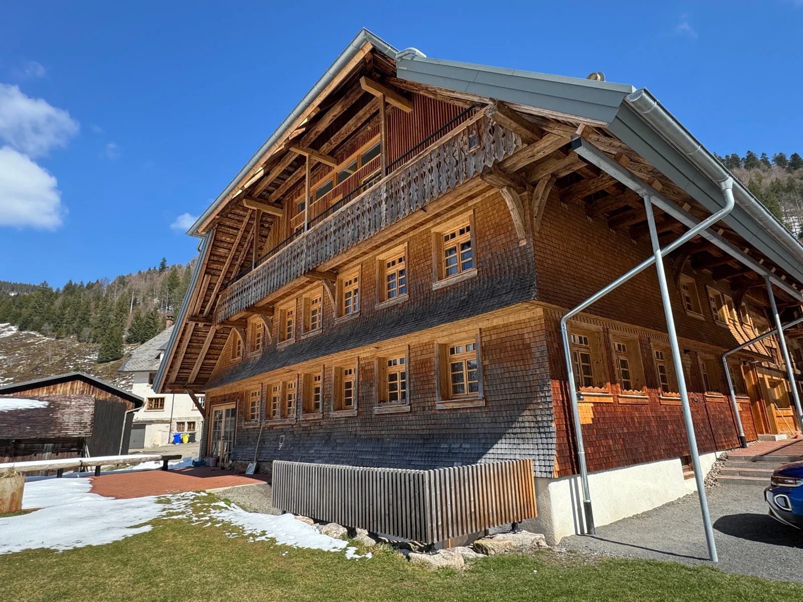Der Bruderhof, ein großes Schwarzwaldhaus mit Holzschindeln und Balkonen, an einem sonnigen Tag mit Schneeresten