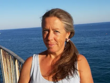 Manu lächelt in die Kamera, hinter ihr das Meer